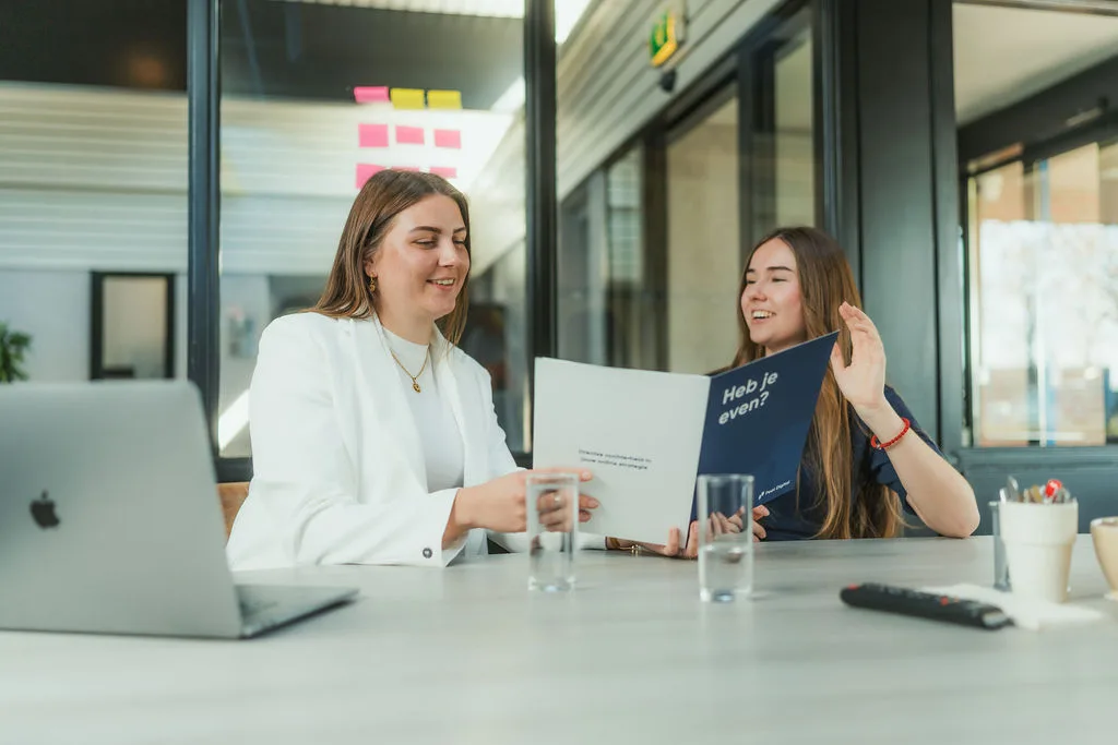 Twee collega's bespreken een brochure aan tafel