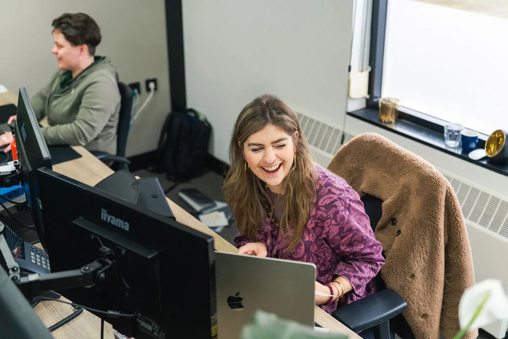 Lachende collega aan het werk achter de laptop