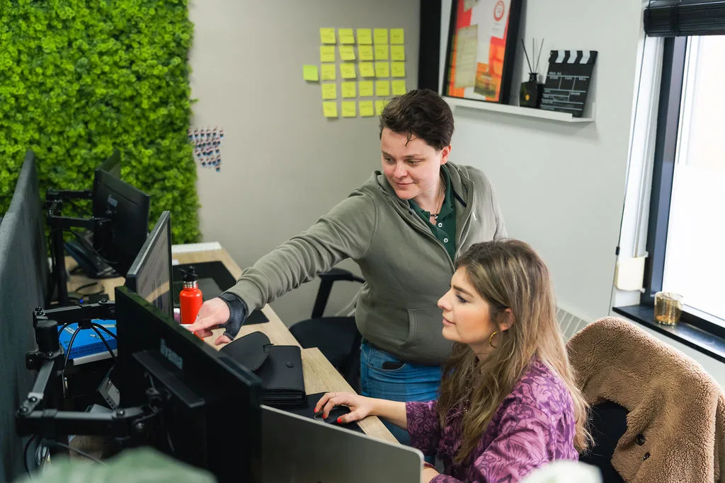 Collega helpt een andere collega achter de computer