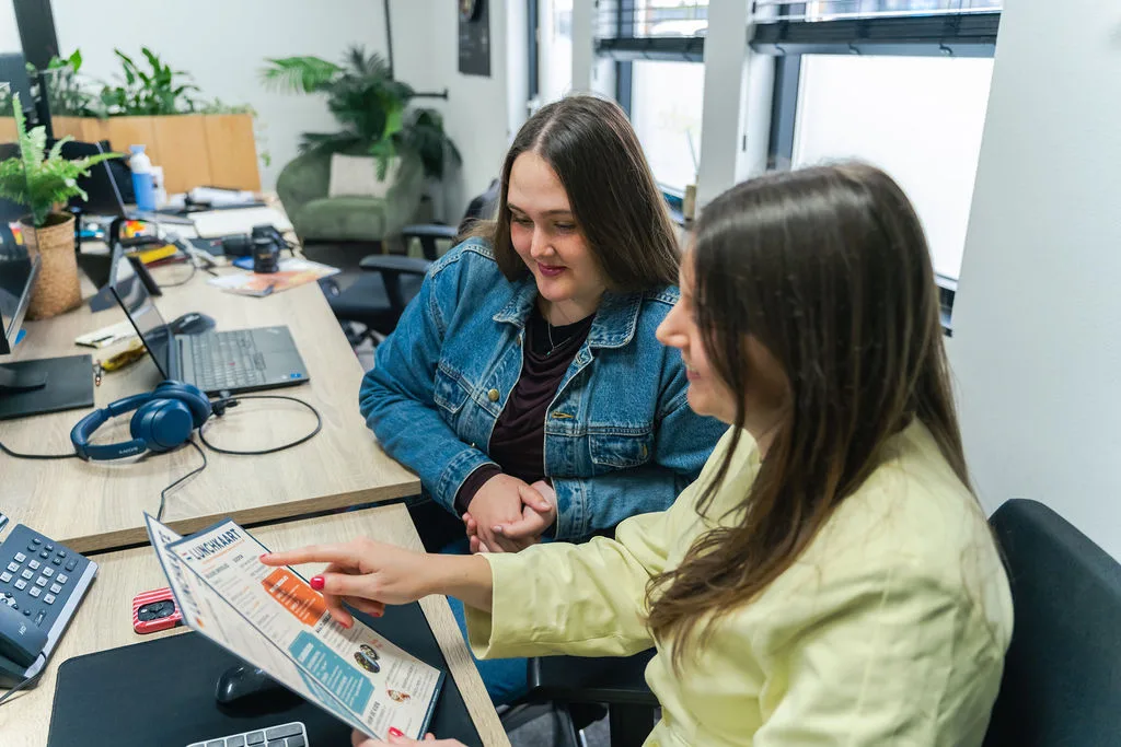 Twee collega's bekijken samen een ontwerp aan het bureau